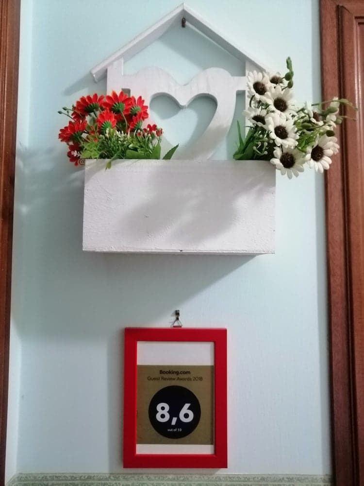 A cozy indoor wall adorned with a heart-shaped flower box and a framed Booking.com guest review award creates a welcoming atmosphere, perfect for travelers seeking a charming accommodation.