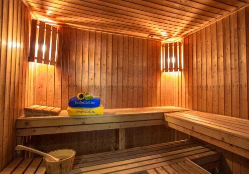 A cozy wooden sauna with warm lighting, benches, and a bucket creates a serene relaxation spot ideal for wellness retreats.