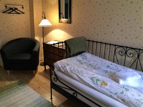 A cozy bedroom with a floral-patterned bedspread, vintage iron bed frame, and warm lighting creates an inviting atmosphere, perfect for travelers seeking a quaint and comfortable stay.