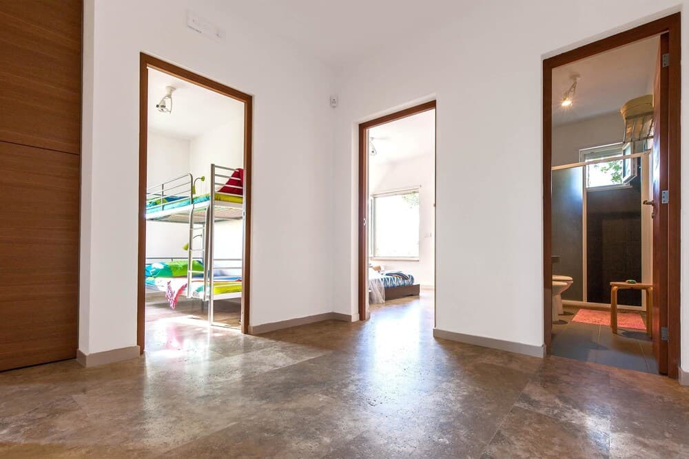 A cozy family-friendly apartment hallway leads to a vibrant bunk bed room, a serene bedroom with natural light, and a modern bathroom, ideal for travelers seeking comfort and convenience.