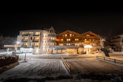 A cozy, warmly lit ski resort building stands invitingly against the snowy night, perfect for winter travelers seeking a serene and comfortable stay.