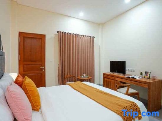 A cozy hotel room features a neatly made bed with colorful pillows, wooden furniture including a desk and chair, and a warm ambiance ideal for travelers seeking comfort and relaxation.