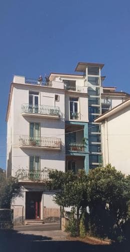 A serene residential building with balconies adorned by greenery under a clear blue sky, ideal for travelers seeking a peaceful urban retreat.