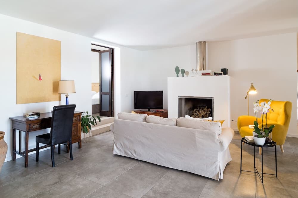 A cozy living room with a white sofa, yellow armchair, fireplace, and desk area exudes warmth and comfort, ideal for travelers seeking a relaxing retreat in a modern vacation rental.