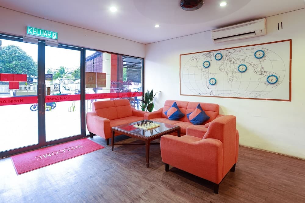 A cozy lounge area with vibrant orange sofas, a chessboard on a glass coffee table, and a world map with time zones, set against large glass doors leading to an outdoor patio, ideal for travelers seeking a comfortable waiting space or meeting spot.