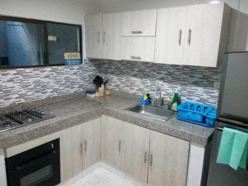A modern kitchen with sleek white cabinets, granite countertops, and a tiled backsplash creates a clean and inviting atmosphere, perfect for travelers seeking a cozy self-catering accommodation.