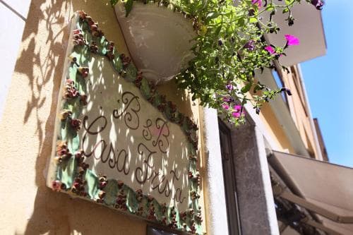 A charming B&B sign adorned with floral decorations hangs on a sunlit wall, evoking a cozy and inviting atmosphere perfect for travelers seeking a quaint European getaway.