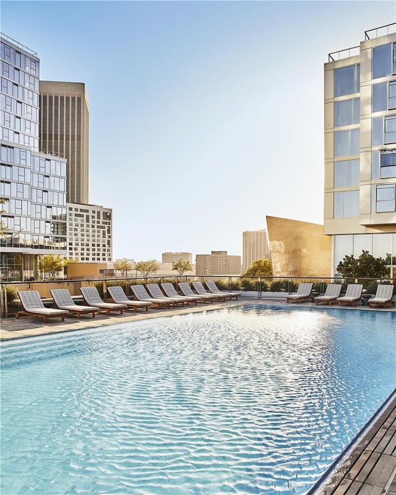 A serene rooftop pool surrounded by lounge chairs offers a luxurious urban retreat against the backdrop of towering skyscrapers, ideal for travelers seeking relaxation in downtown Los Angeles.
