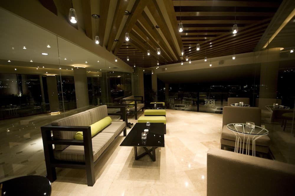 A cozy lounge area with modern sofas, glass tables, and warm lighting creates an inviting atmosphere in a luxurious indoor setting, perfect for travelers seeking relaxation or business meetings.