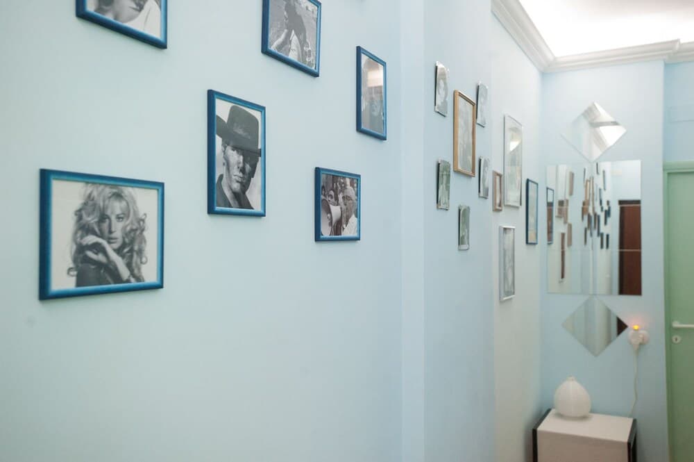 A serene hallway adorned with framed black-and-white portraits and geometric mirrors creates an artistic ambiance ideal for boutique hotel decor inspiration.