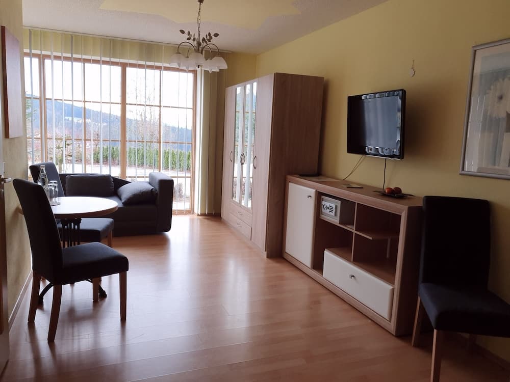 A cozy living room with wooden floors, modern furniture, and large windows offering scenic mountain views, ideal for travelers seeking relaxation in a serene vacation rental.