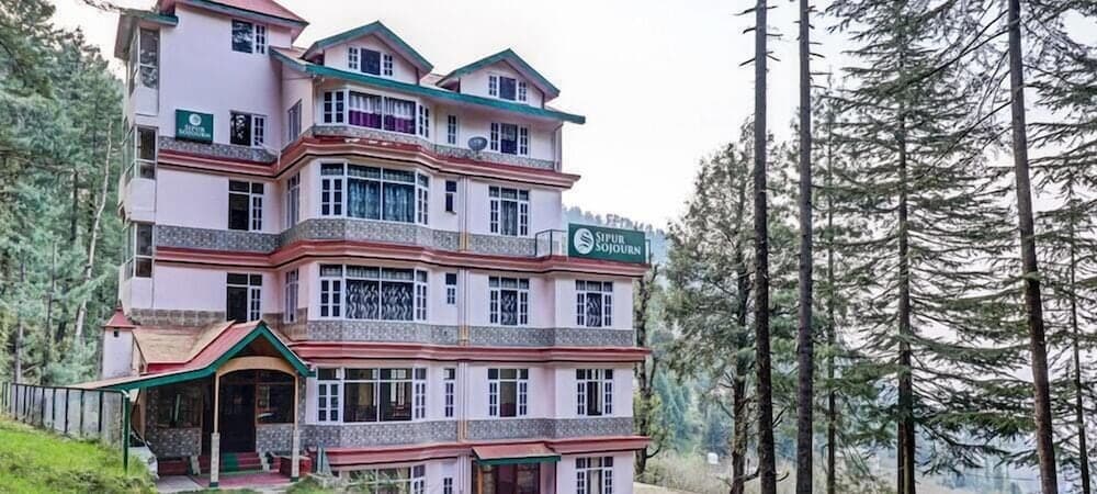 A serene multi-story hotel nestled amidst lush pine forests offers a tranquil retreat for travelers seeking nature-inspired relaxation.