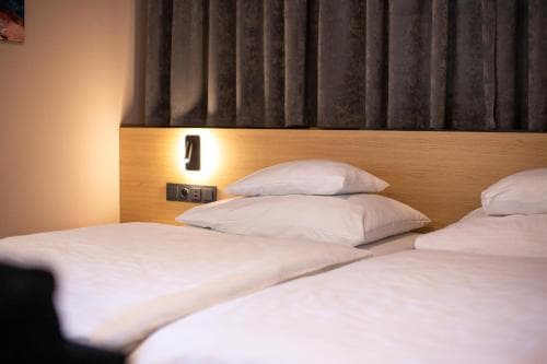 A cozy hotel room features two neatly made beds with white linens under warm ambient lighting, ideal for travelers seeking comfort and relaxation.