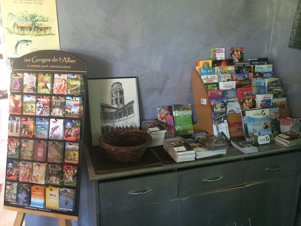 A cozy indoor tourist information desk displays colorful brochures, maps, and a wicker basket against a rustic backdrop, ideal for travelers seeking cultural and recreational activities in scenic regions.