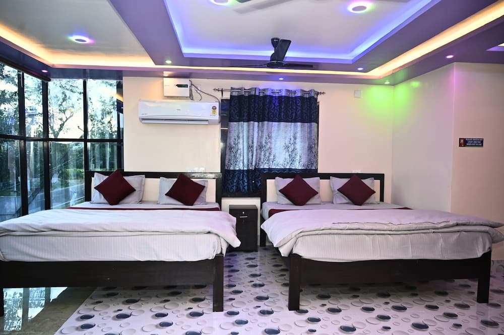 A cozy hotel room features two neatly made beds with maroon accents, colorful LED lighting, a patterned floor, and large windows offering a serene outdoor view, ideal for travelers seeking comfort and relaxation.