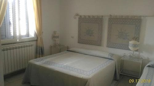 A cozy hotel room features a neatly made bed adorned with blue patterns, framed by soft yellow curtains and decorative wall art, ideal for travelers seeking a tranquil retreat.
