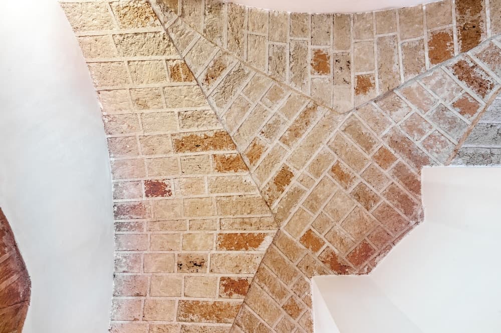 A close-up of an intricately patterned brick wall in a serene indoor setting, featuring geometric designs and earthy tones, ideal for travelers exploring architectural details and design inspiration.
