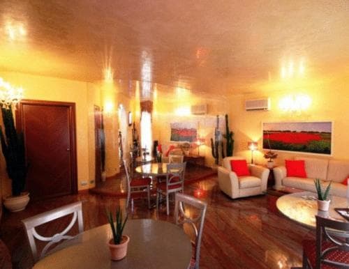 A cozy living room with warm lighting, wooden floors, modern furniture, and vibrant artwork creates an inviting atmosphere ideal for travelers seeking a comfortable stay in a stylish apartment.