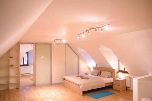 A cozy attic bedroom with sloped ceilings, wooden flooring, and modern furnishings creates a serene retreat, ideal for travelers seeking a unique and comfortable stay in a boutique accommodation.