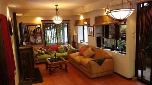 A cozy living room with warm lighting, comfortable sofas, and large windows overlooking greenery, ideal for travelers seeking a relaxing retreat in an urban apartment setting.