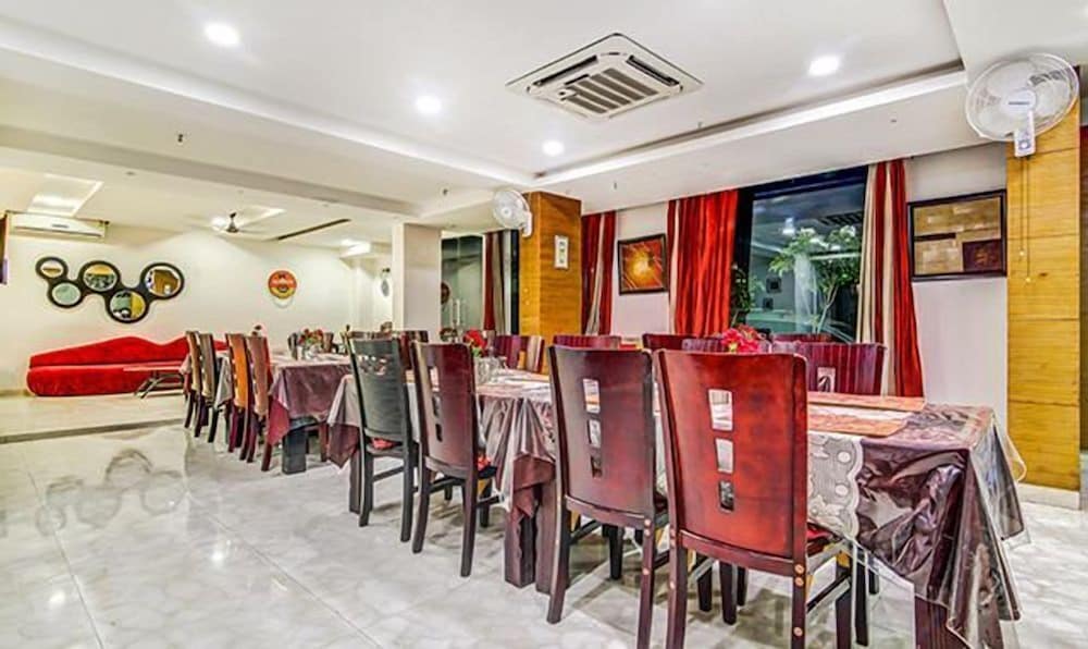 A cozy indoor dining area features polished marble floors, red-cushioned chairs, patterned tablecloths, and vibrant decor, creating an inviting atmosphere ideal for travelers seeking a comfortable meal spot.