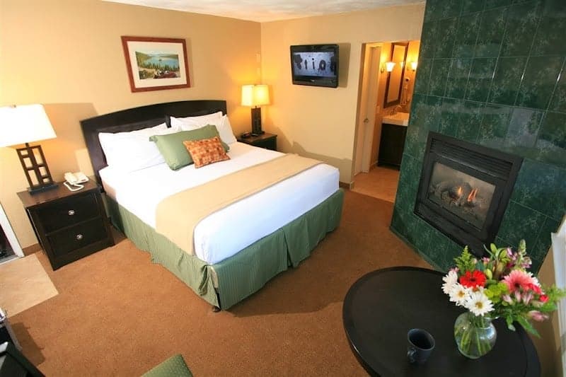 A cozy hotel room in South Lake Tahoe features a warm fireplace, inviting bed setup, and vibrant floral decor, perfect for travelers seeking comfort and relaxation.