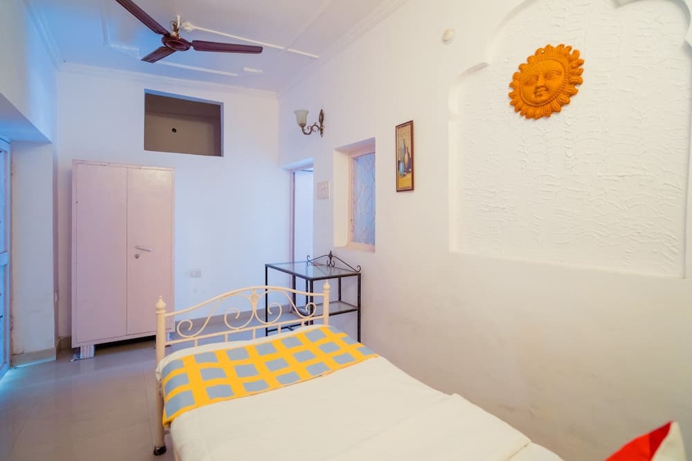 A cozy bedroom with white walls, a sun-shaped wall decoration, and a vibrant yellow and blue bedspread invites travelers seeking a charming and comfortable stay.