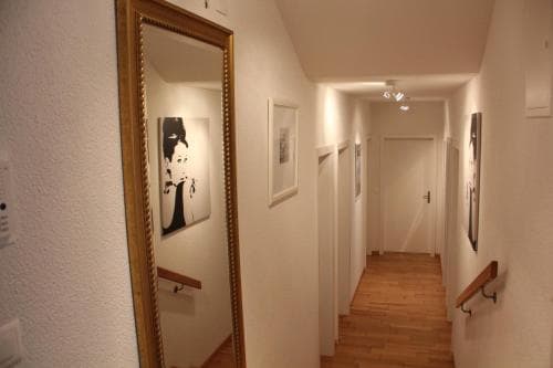 A warmly lit hotel corridor adorned with framed artwork and wooden flooring invites travelers to explore its cozy and artistic ambiance.