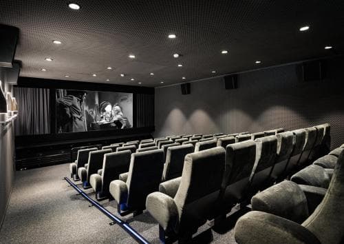 A cozy movie theater with plush reclining seats and dim lighting creates an inviting atmosphere for travelers seeking entertainment during downtime.