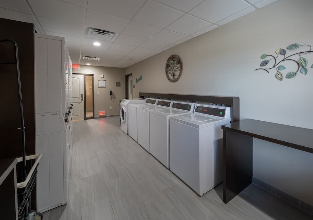 A clean and organized laundry room with white appliances, wooden flooring, and decorative wall art offers a convenient and welcoming space for travelers to refresh their clothes during their stay.