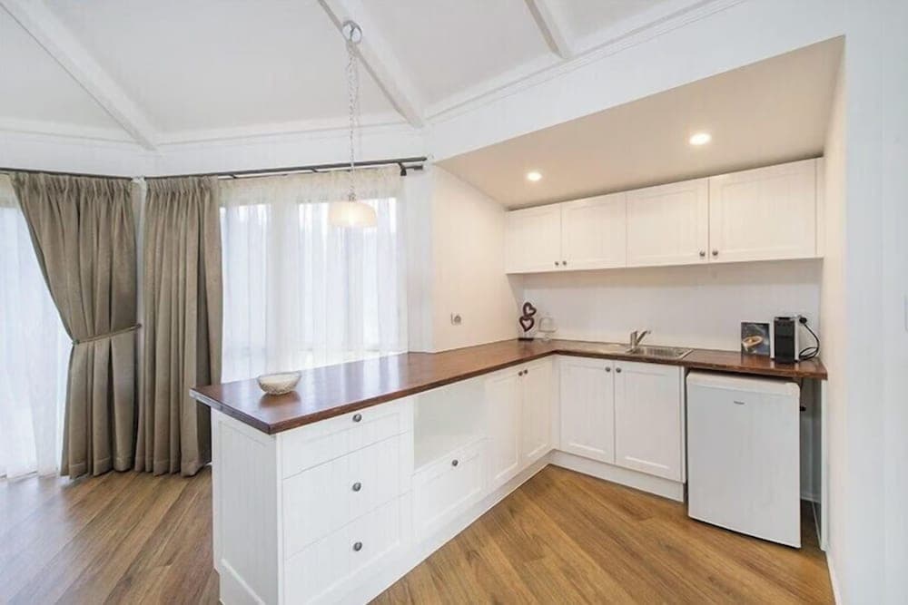 A cozy, modern kitchen with white cabinetry, wooden countertops, and soft lighting creates an inviting atmosphere ideal for travelers seeking a comfortable self-catering accommodation.