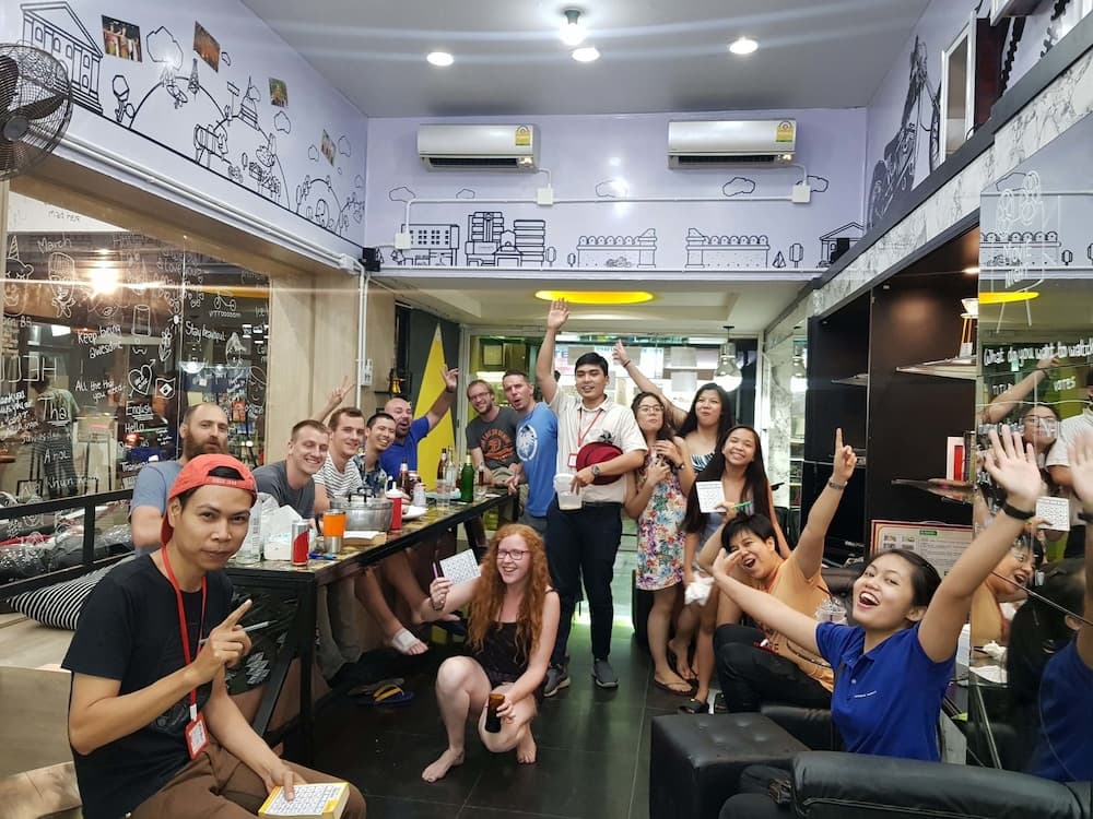 A lively group celebrates in a cozy café adorned with playful wall art, ideal for travelers seeking a fun social spot with drinks and camaraderie.