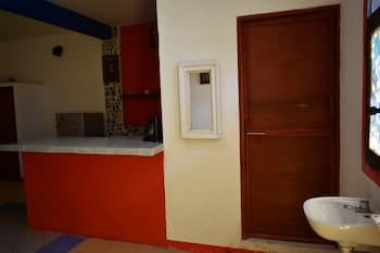 A cozy indoor space featuring a vibrant red counter, wooden door, and colorful tiled accents, evokes a warm, inviting atmosphere ideal for travelers seeking a quaint local café or small restaurant experience.