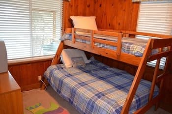 A cozy cabin bedroom with wooden bunk beds featuring blue plaid bedding, set against warm wood-paneled walls, ideal for family retreats seeking comfort and rustic charm.