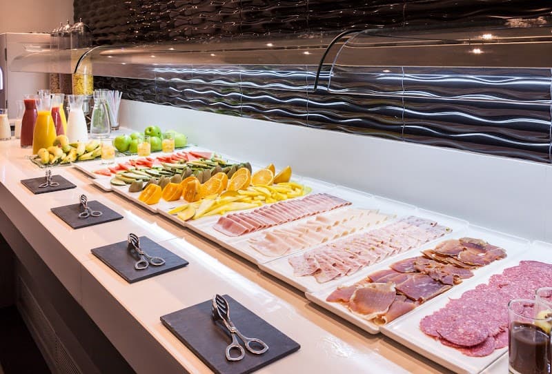 A vibrant buffet spread featuring fresh fruits, sliced meats, and colorful beverages invites guests to indulge in a delightful dining experience at a modern hotel setting, perfect for travelers seeking convenience and culinary variety during their stay.