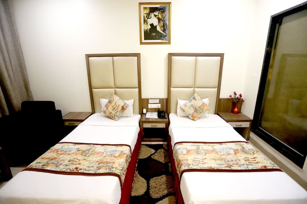 A cozy hotel room features two neatly made twin beds with patterned throws, a framed artwork above, and a warm ambiance ideal for travelers seeking comfort and relaxation.