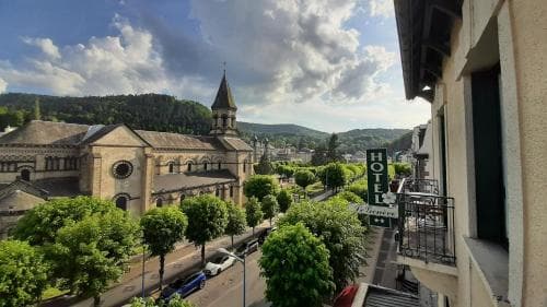 A picturesque European town scene featuring a historic church with a spire, lush greenery, and a hotel sign, evoking a serene and inviting atmosphere ideal for cultural exploration and relaxation.