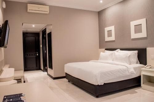 A cozy hotel room features a neatly made bed, minimalist decor, and a modern bathroom entrance, ideal for travelers seeking comfort and simplicity during their stay.