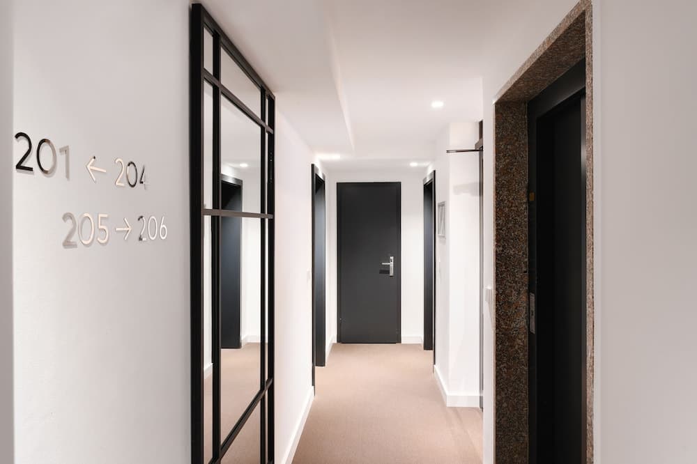 A modern hotel corridor with sleek black doors, numbered room signs, and a carpeted floor offers a clean and inviting atmosphere for travelers seeking comfortable accommodations.