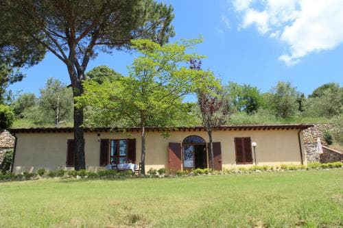 A serene countryside villa with a rustic charm, surrounded by lush greenery under a bright blue sky, offers an idyllic retreat for travelers seeking relaxation and nature immersion.
