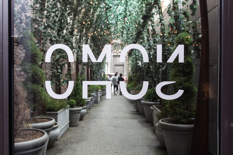 A serene urban oasis at NOMO SOHO in New York City features lush greenery, potted plants, and twinkling lights, creating an inviting atmosphere ideal for travelers seeking a tranquil retreat.