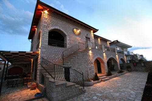 A charming stone villa with arched doorways and balconies glows warmly under evening lights, creating an inviting atmosphere ideal for travelers seeking a cozy retreat in a quaint village setting.