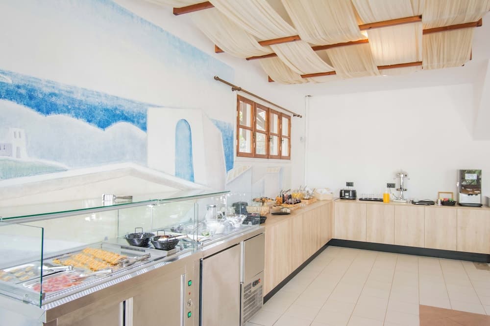 A serene breakfast area features a mural of blue landscapes, wooden accents, and a buffet setup with pastries and beverages, ideal for travelers seeking a cozy morning start in a resort or hotel setting.