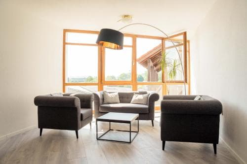 A cozy modern living room with sleek furniture and large windows offering a serene view of greenery, ideal for travelers seeking a tranquil accommodation experience.
