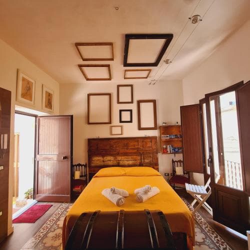 A cozy bedroom with warm yellow tones, wooden furnishings, and framed artwork exudes a serene atmosphere, perfect for travelers seeking a charming and inviting accommodation experience.