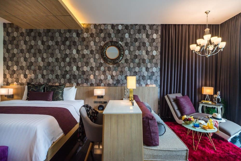 A cozy hotel room features a stylish hexagonal-patterned wall, plush seating, and warm lighting, creating an inviting atmosphere perfect for travelers seeking comfort and relaxation.