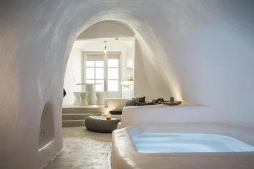 A serene cave-style bedroom with a sunken bathtub, arched ceilings, and soft lighting creates an intimate retreat ideal for luxury relaxation getaways.