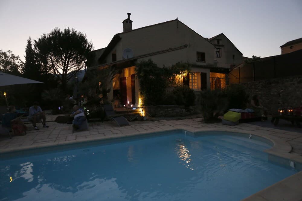 A serene evening at a cozy villa with a tranquil pool, warm outdoor lighting, and guests enjoying the ambiance, ideal for a relaxing vacation retreat.