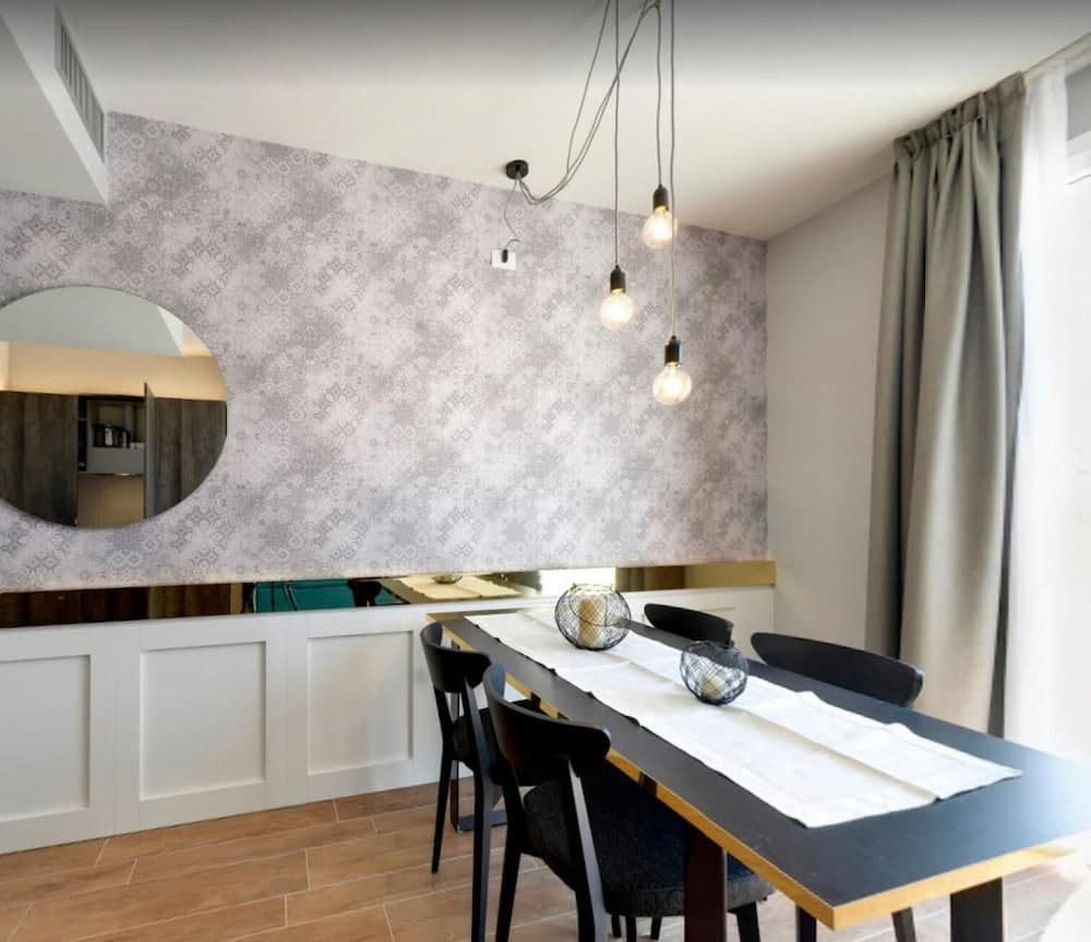 A cozy dining area features a sleek black table with decorative glass orbs, set against a patterned wall with an artistic cutout mirror, creating a modern and inviting atmosphere ideal for travelers seeking stylish accommodations.