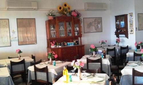 A cozy restaurant interior features wooden furniture adorned with vibrant floral arrangements, creating an inviting atmosphere ideal for travelers seeking a warm dining experience.